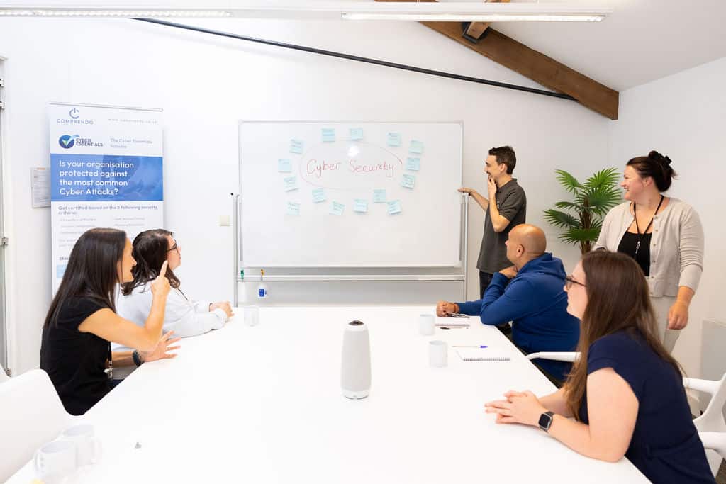 The Comprendo IT team training a client on cybersecurity in a meeting room with a whiteboard