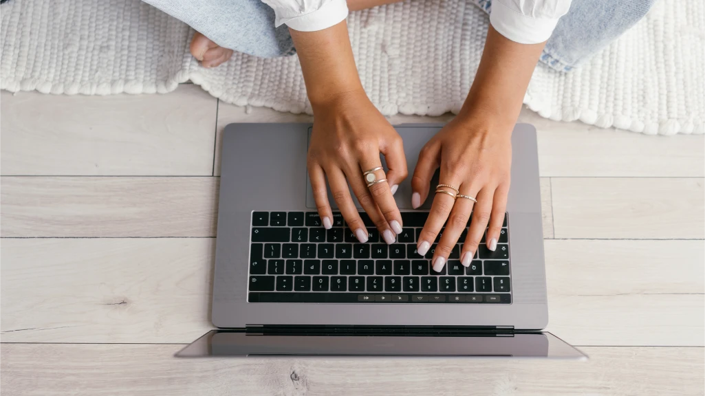 Top view of a woman using her laptop to read her marketing emails just showing the laptop and hands