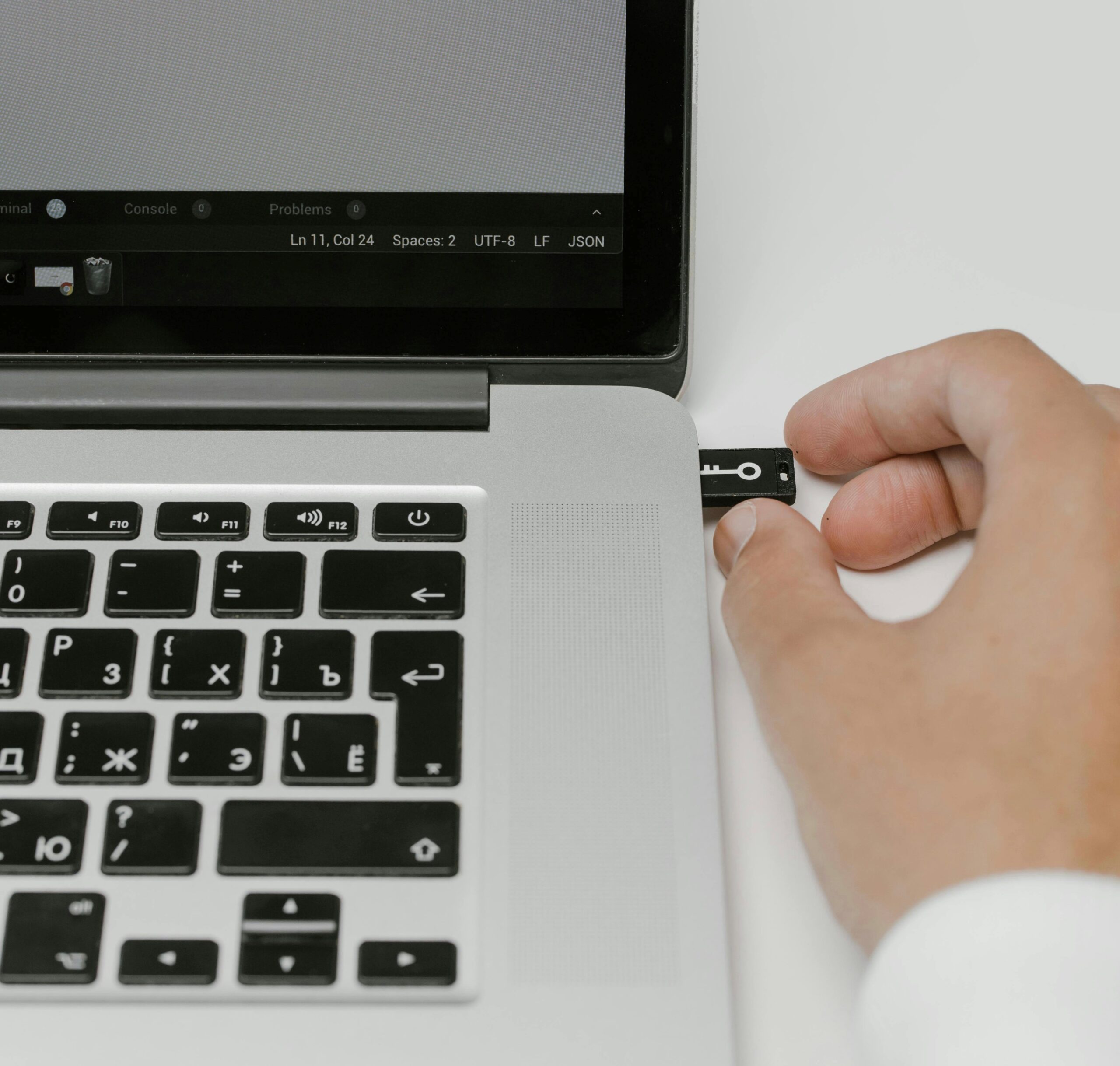 a hand putting a USB stick into the side of a laptop