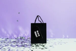 black 'sale' shopping bag on lilac background with confetti