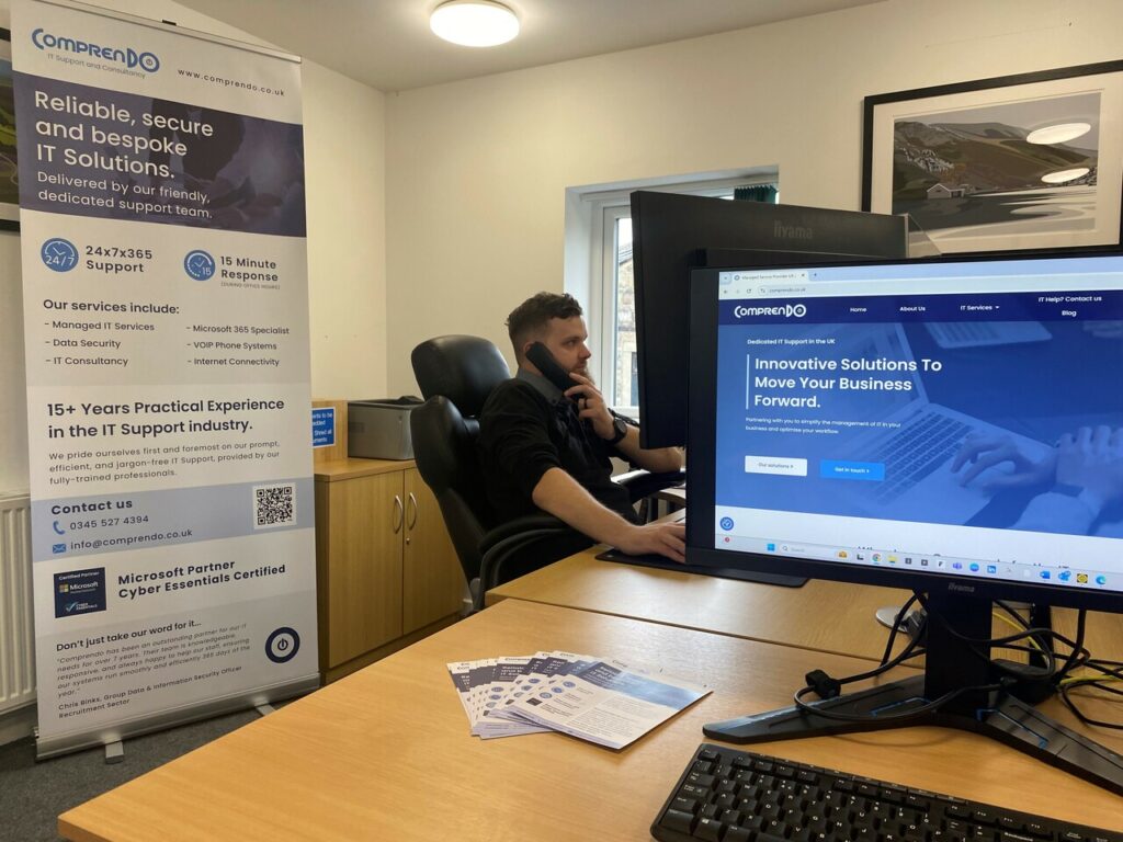 Our technician Zack Thompson sitting at his desk in the Comprendo offices, on the telephone.