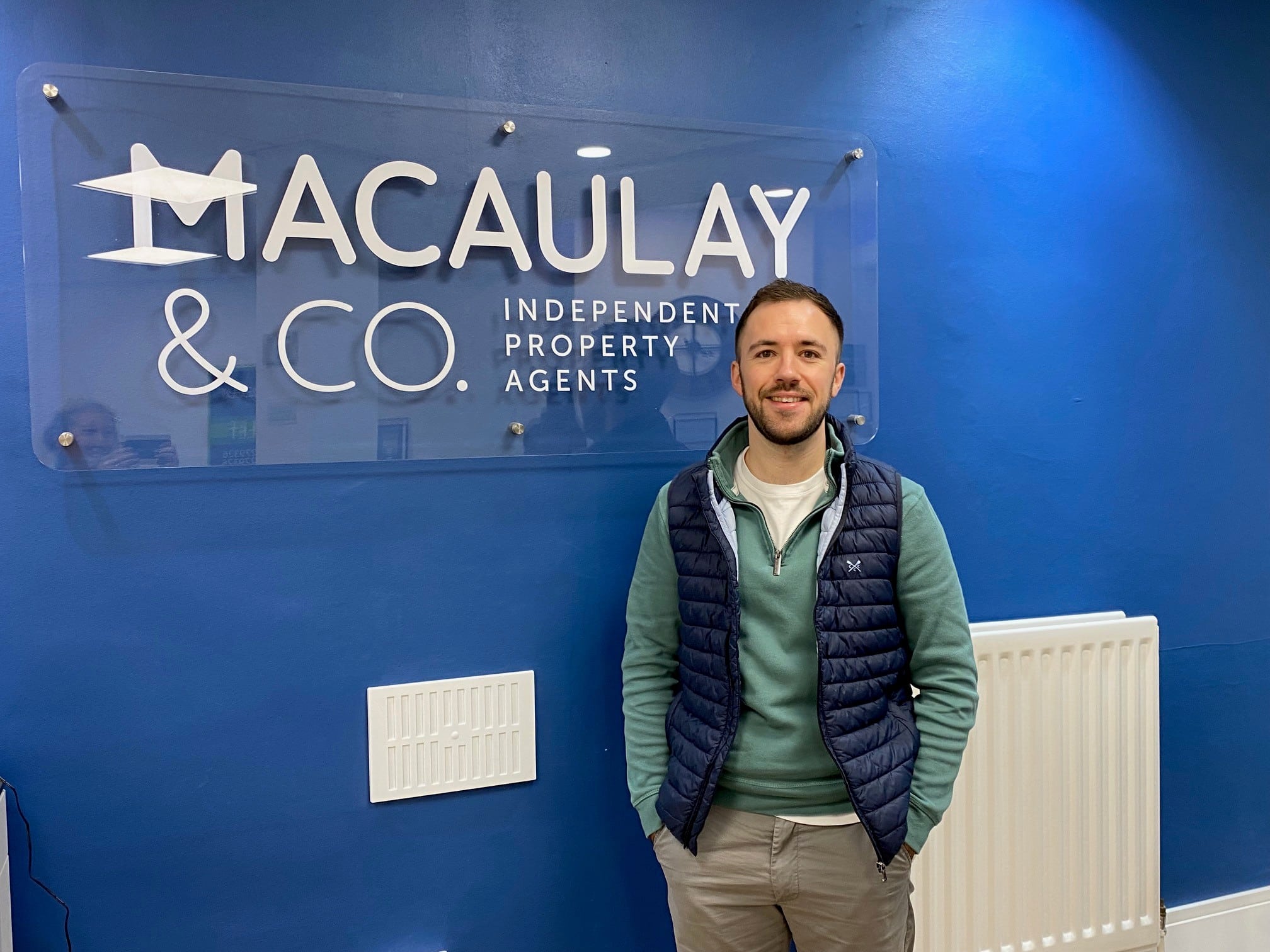 Owner of Macaulay & Co in front of his signage